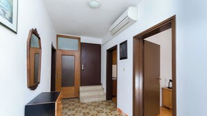 A hallway with a wooden door, a mirror, and a small cabinet. - Apartments Ruza A (Lopar)