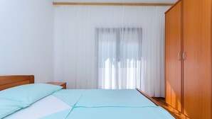 A bedroom with a bed, wooden wardrobe, and a nightstand. - Apartments Ruza A (Lopar)