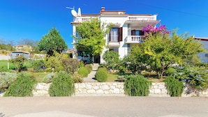A two-story house with a stone wall and a small garden in front.