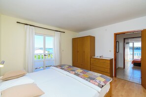 Una camera da letto con un letto, un armadio in legno, una finestra con tende e vista sull'esterno.