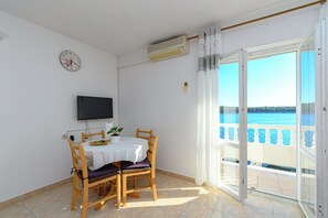 Un balcone con vista sul mare, un tavolo con sedie, una televisione e un condizionatore.