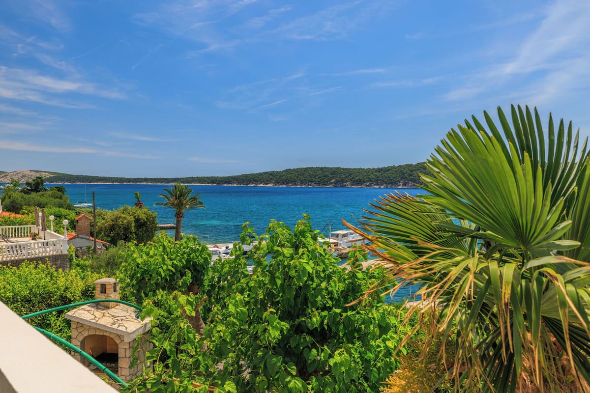 Une vue sur la côte, avec une construction en pierre, une végétation luxuriante et une mer bleue et limpide.
