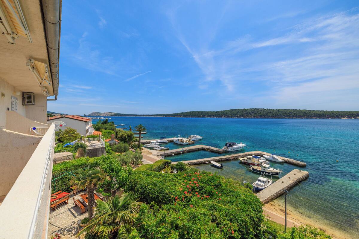 Une vue sur la côte, avec un port de plaisance, des bateaux et un bâtiment doté d’un balcon donnant sur la mer.