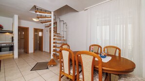 Un comedor con una mesa y sillas de madera, una cocina con horno, y una escalera en espiral.