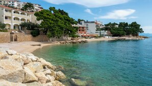Un hotel costero con varios balcones, una pared de piedra y vista despejada al mar.