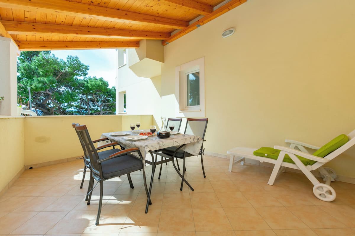 A dining area with a table, chairs, and a sun lounger.