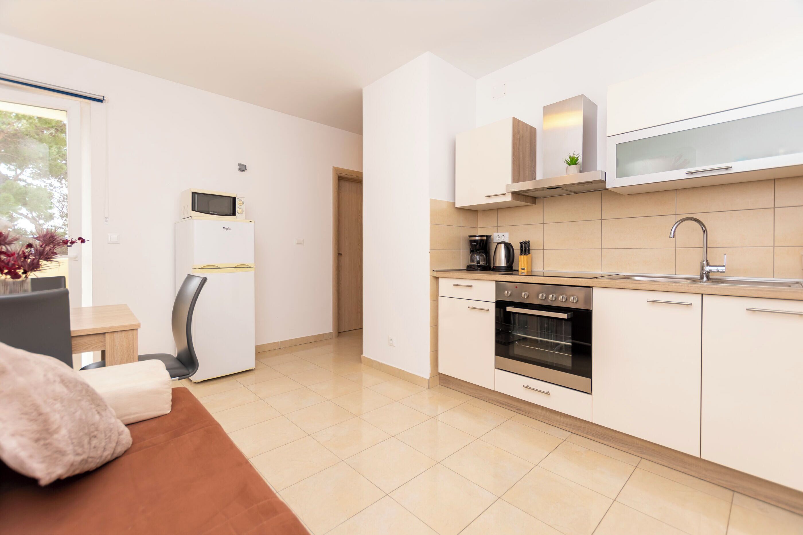 A modern kitchen with white cabinets, a built-in oven, and a microwave.