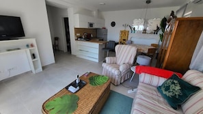 A modern living room with a sofa, a television, a kitchen area, and a dining table. - Apartments Livingston (Novi Vinodolski)