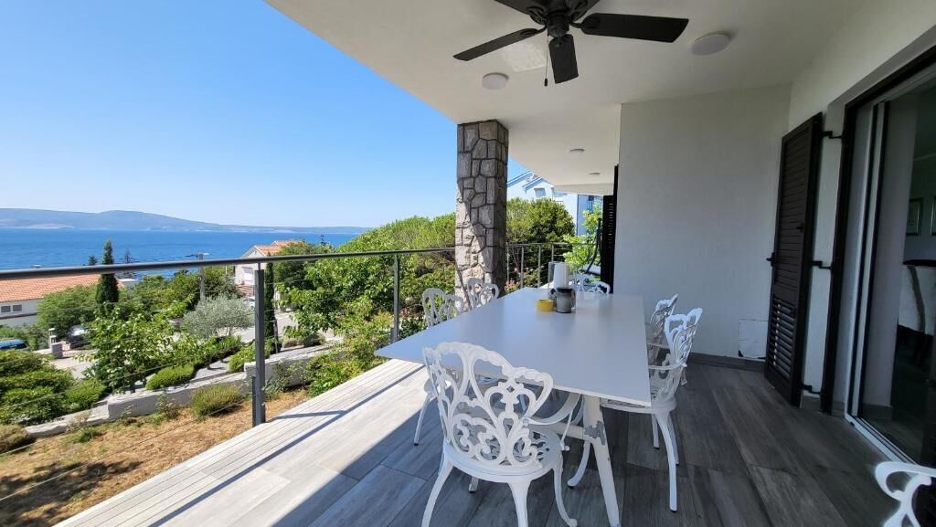 Un balcon avec une table et des chaises, un ventilateur de plafond et un pilier en pierre.