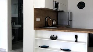 Una cucina moderna con mobili bianchi, un piano di lavoro in legno e un forno a microonde integrato.
