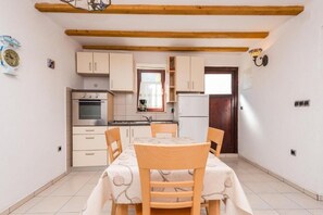Eine gemütliche Küchenzeile mit Holzbalken, einem Esstisch mit Stühlen und einem Kühlschrank.