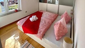 Ein Schlafzimmer mit einem Bett, einem Fenster, einer Deckenleuchte und einer Wand-Klimaanlage.
