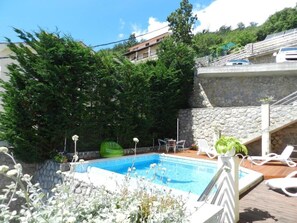 Piscina com espreguiçadeiras e um muro de pedra.
