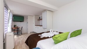 A hotel room with a bed, a desk, a chair, a television, and a wardrobe. - Apartments Ana (Brela)