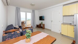 A compact living space with a sofa, dining table, kitchen area, and a TV. - Apartments Ana (Brela)