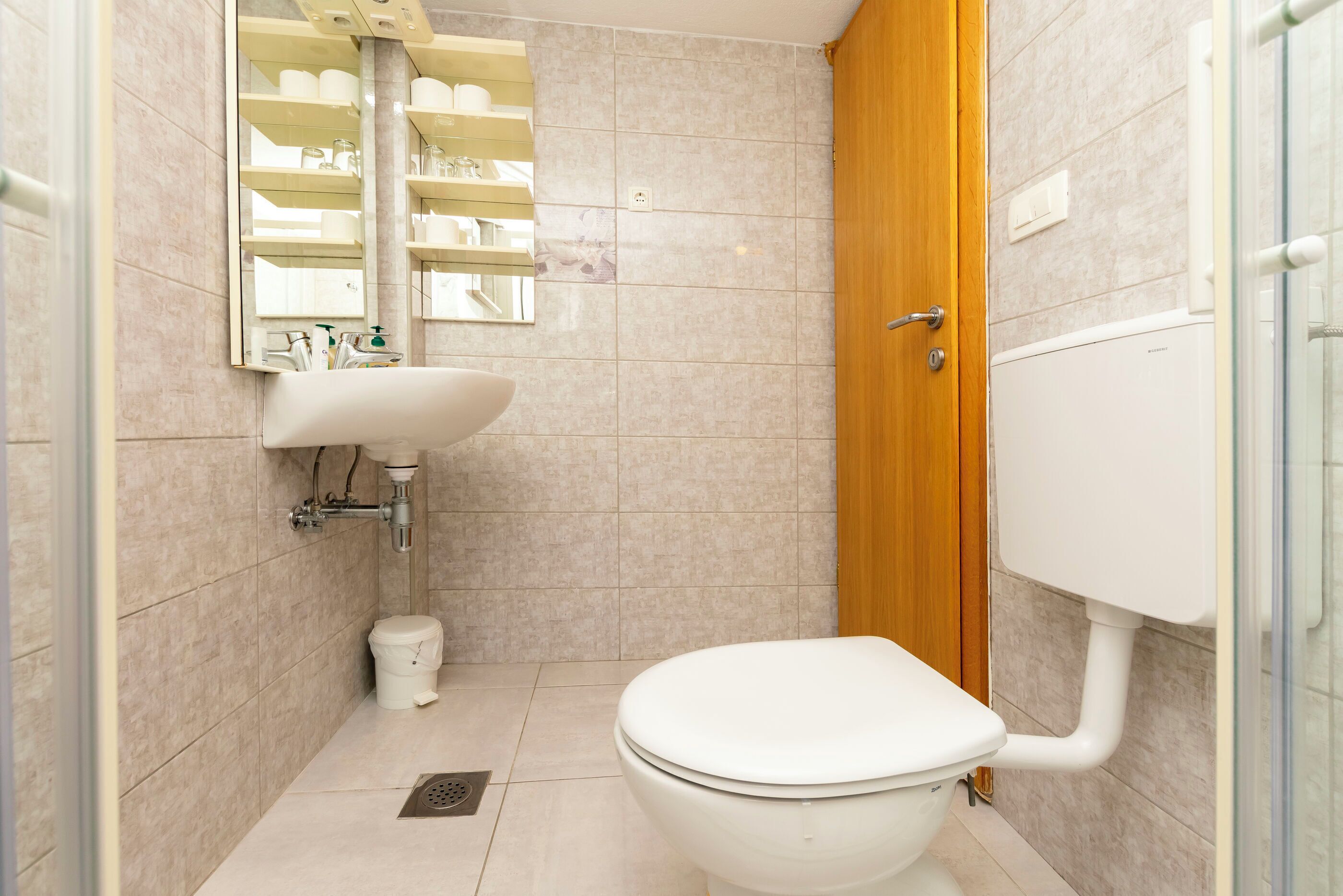 Une petite salle de bain moderne, équipée de toilettes, d’un lavabo et d’un miroir.