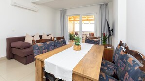 A dining area with a wooden table, white tablecloth, and patterned chairs. - Apartments Ana (Brela)