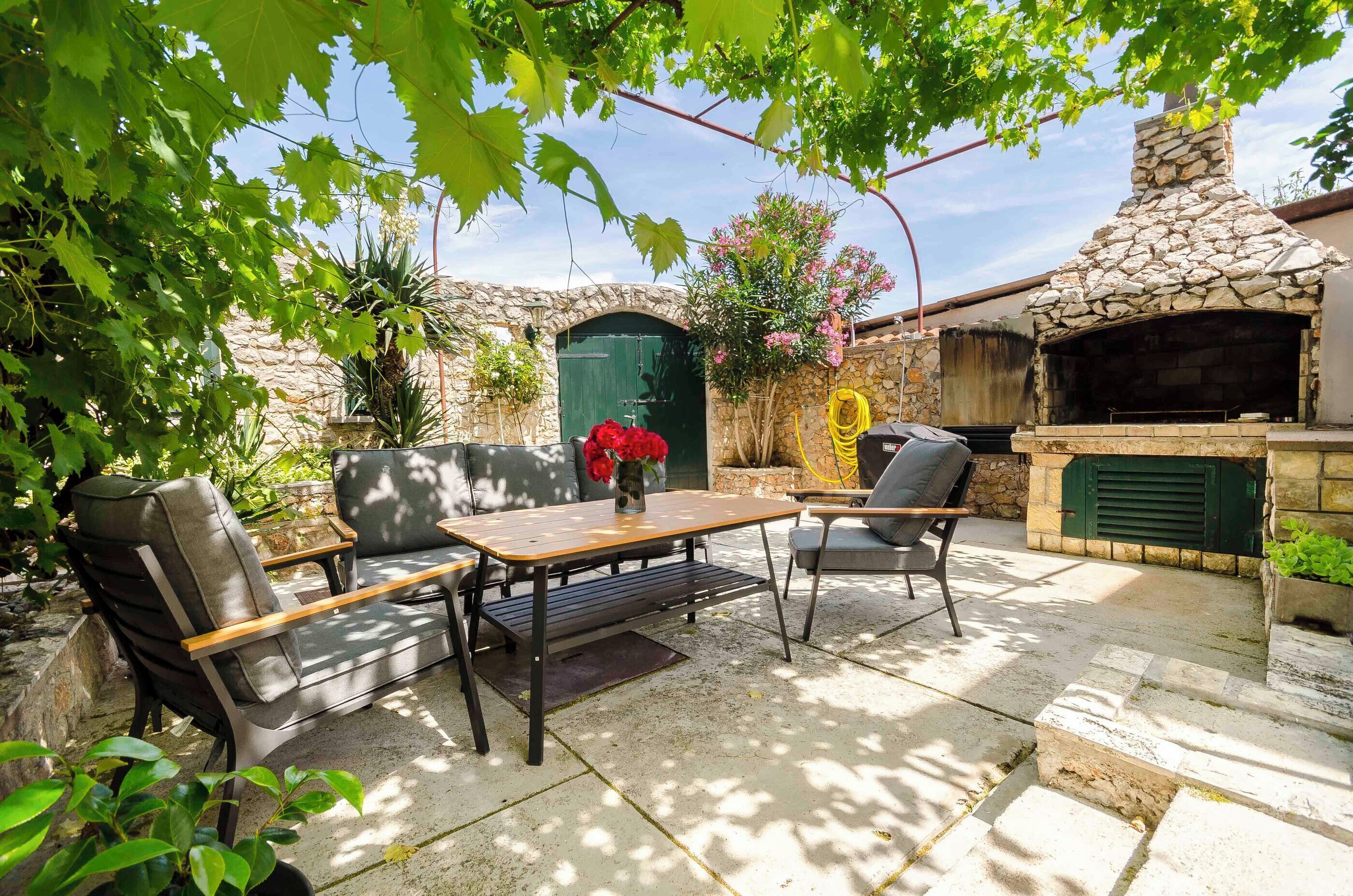 Une terrasse extérieure avec des murs en pierre, une cheminée en pierre et des sièges.