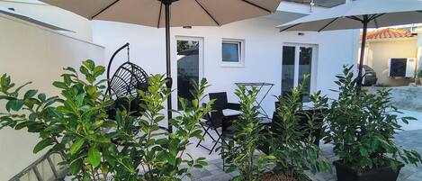 A patio with outdoor furniture, potted plants, and umbrellas.