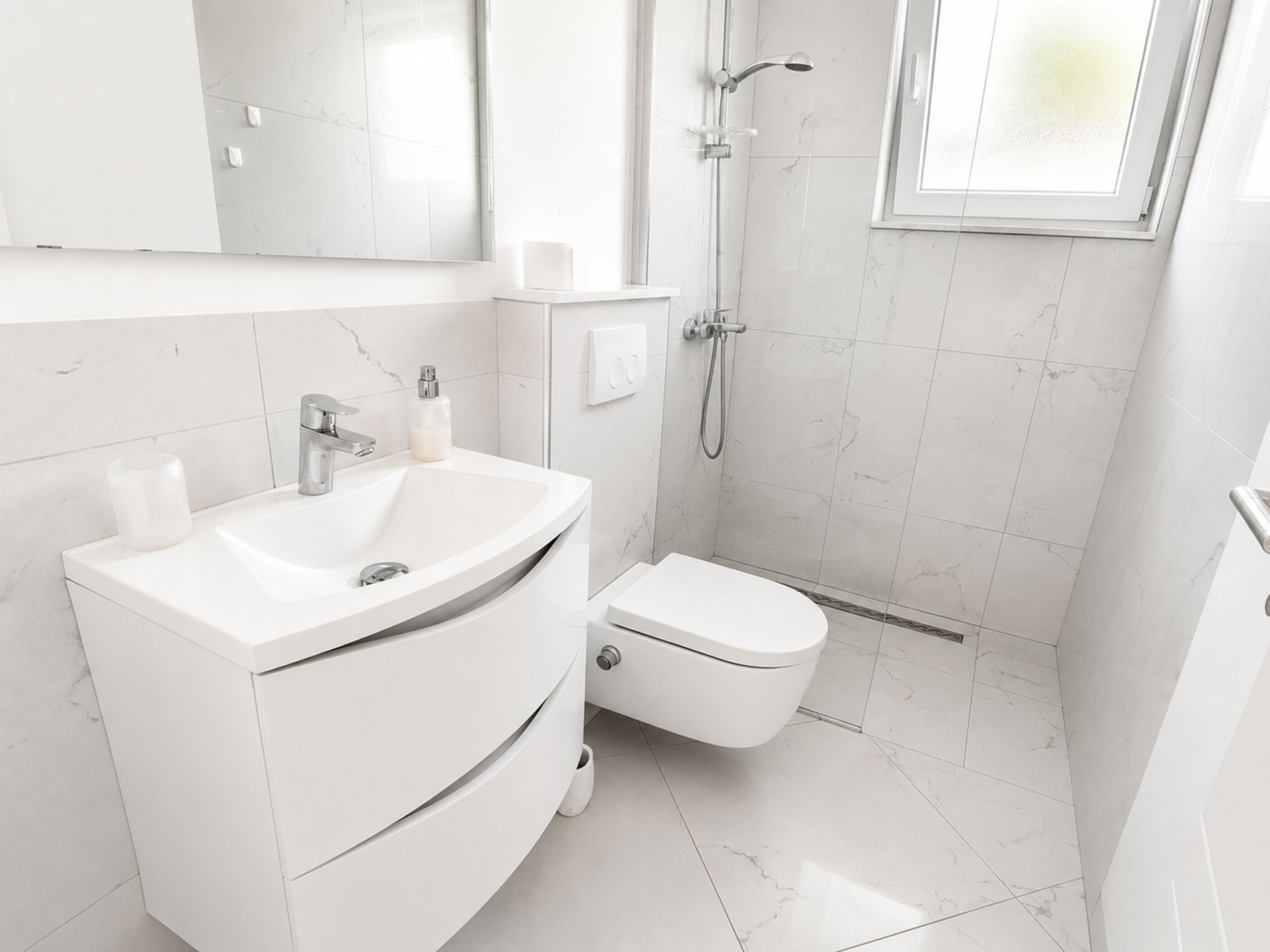 A modern bathroom with a white vanity, toilet, and shower.