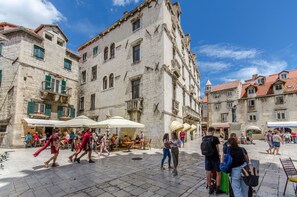 A historic square with stone buildings, outdoor seating, and people walking. - Apartment City Light (Split)