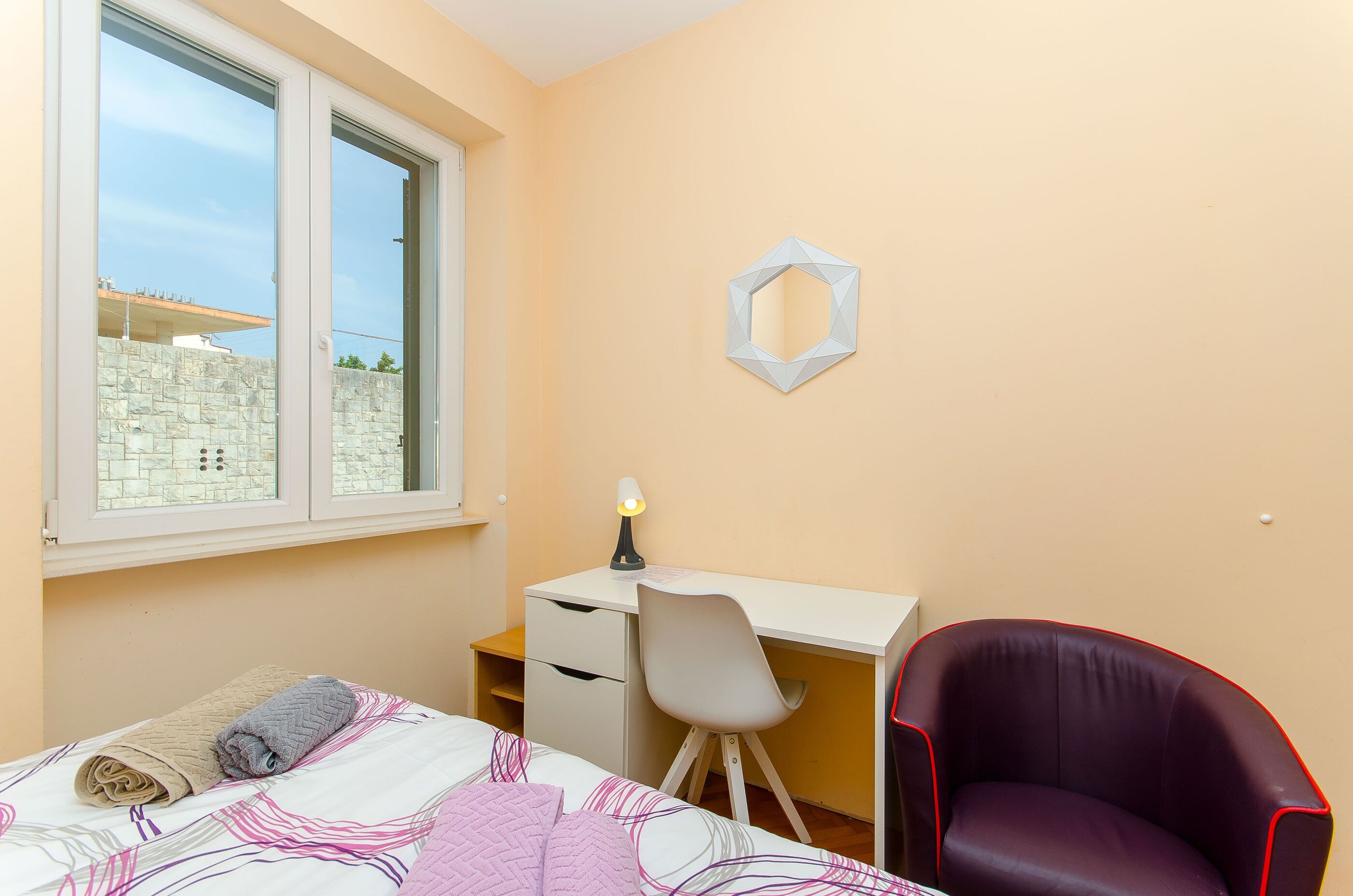 Un dormitorio con cama, escritorio y silla.
