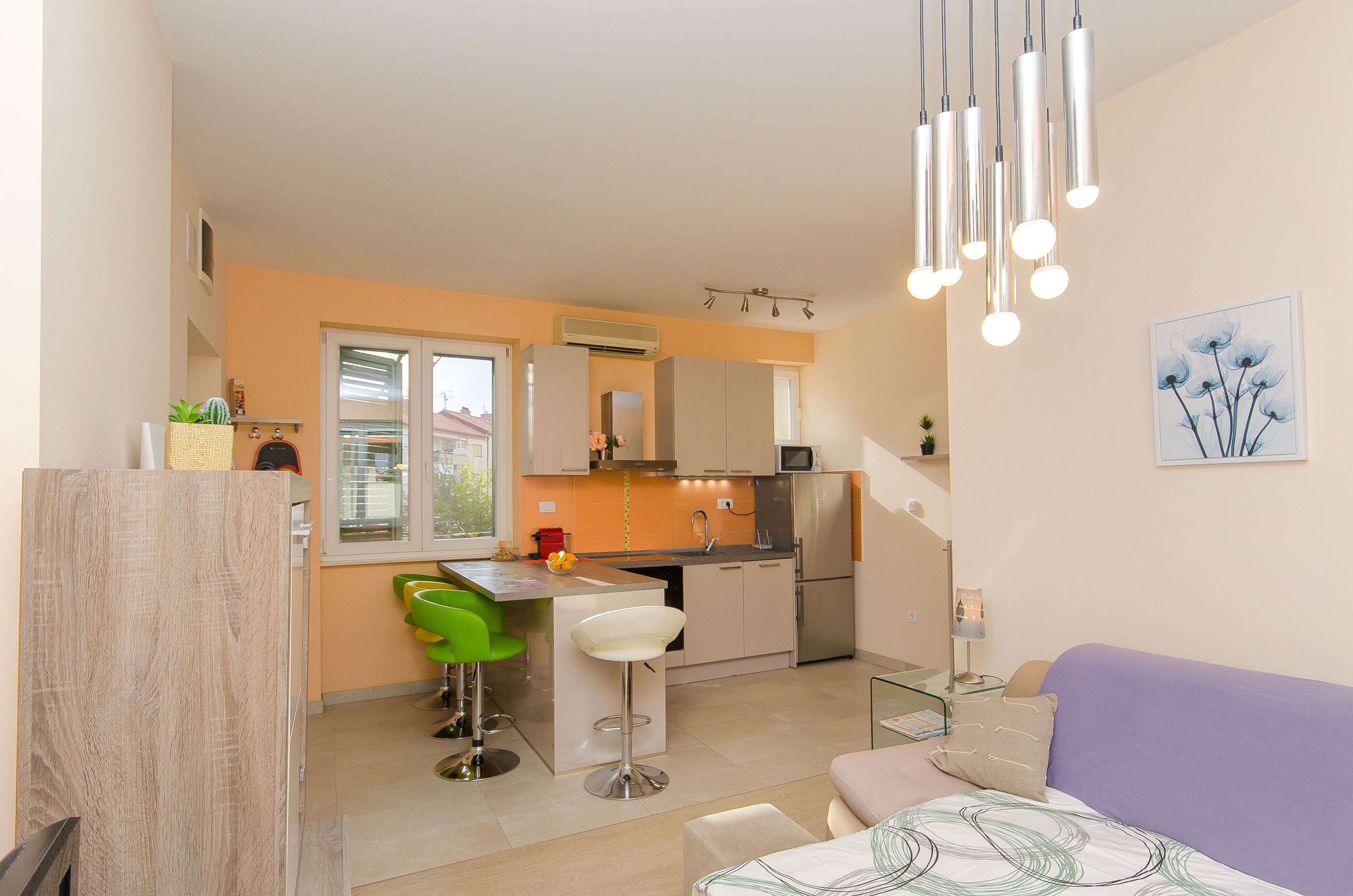 Cocina compacta con comedor, sofá y una pequeña mesa con lámpara.