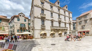A historic building with multiple balconies and arched windows, surrounded by a public square with cafes and outdoor seating. - Apartment City Light (Split)