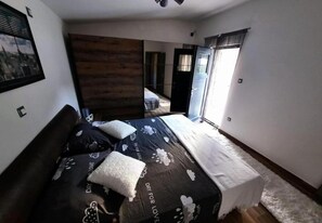 Un dormitorio con cama, pared decorativa de madera, ventana con cortinas y vista al exterior.