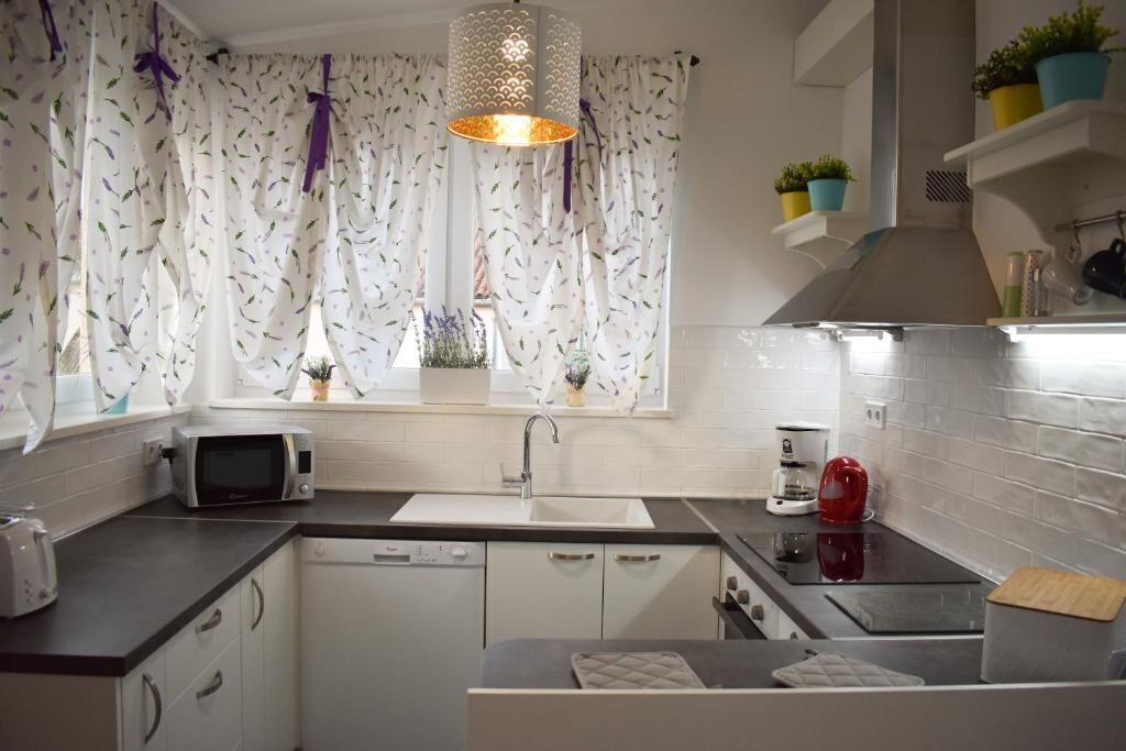 Una cocina moderna con armarios blancos, un microondas, un fregadero y una cafetera roja.