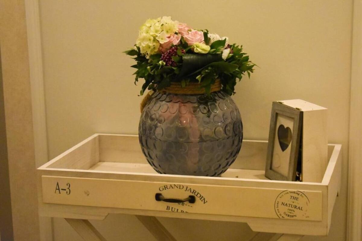Un vaso decorativo con fiori su un vassoio di legno etichettato 'A-3'.