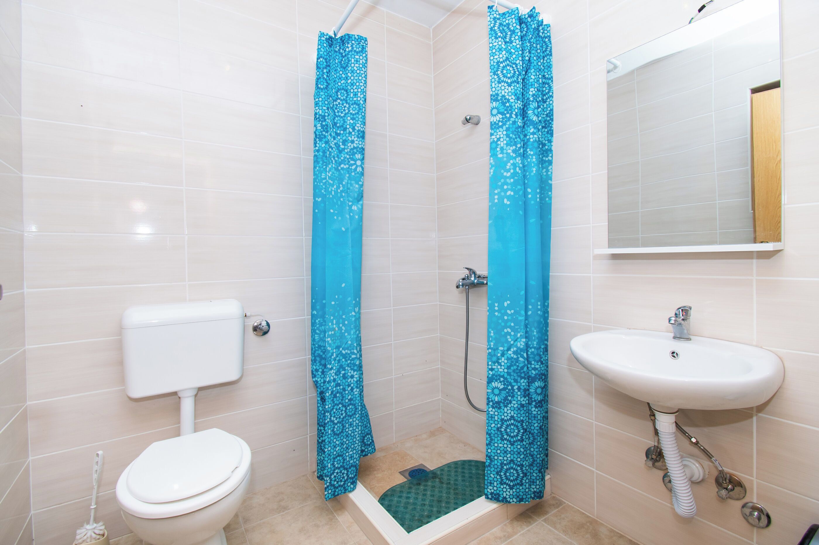 A bathroom with a toilet, shower, and sink.