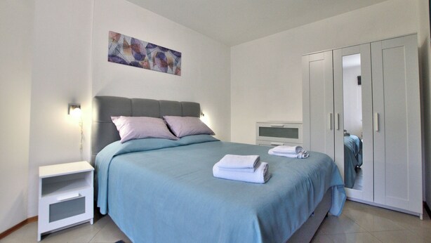 Una camera da letto con un letto, un comodino, un armadio e un quadro appeso al muro.