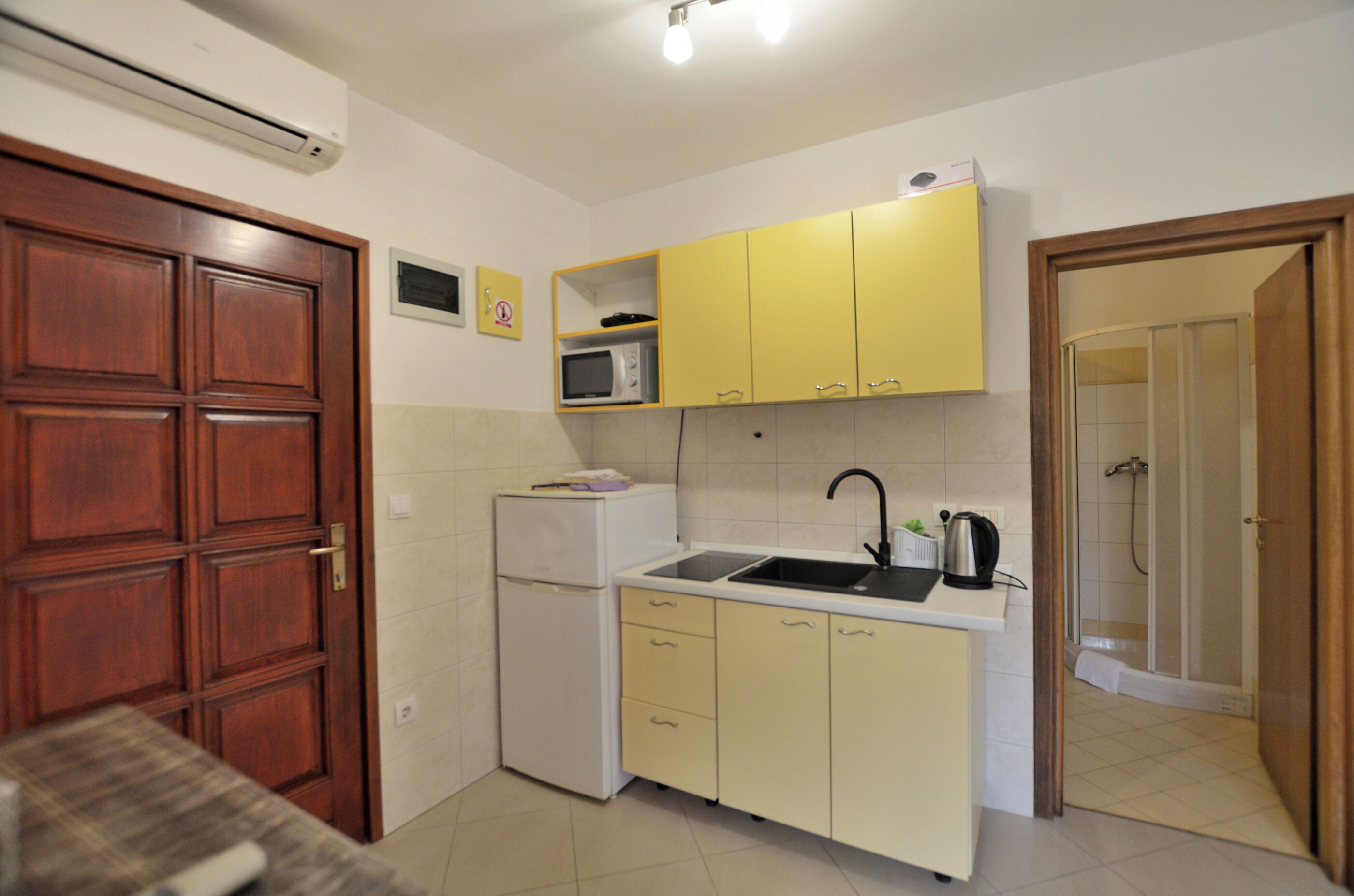 A compact kitchen with a refrigerator, microwave, sink, and wooden cabinets.