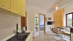 Una cucina con lavello, bollitore e zona pranzo con tavolo e sedie.