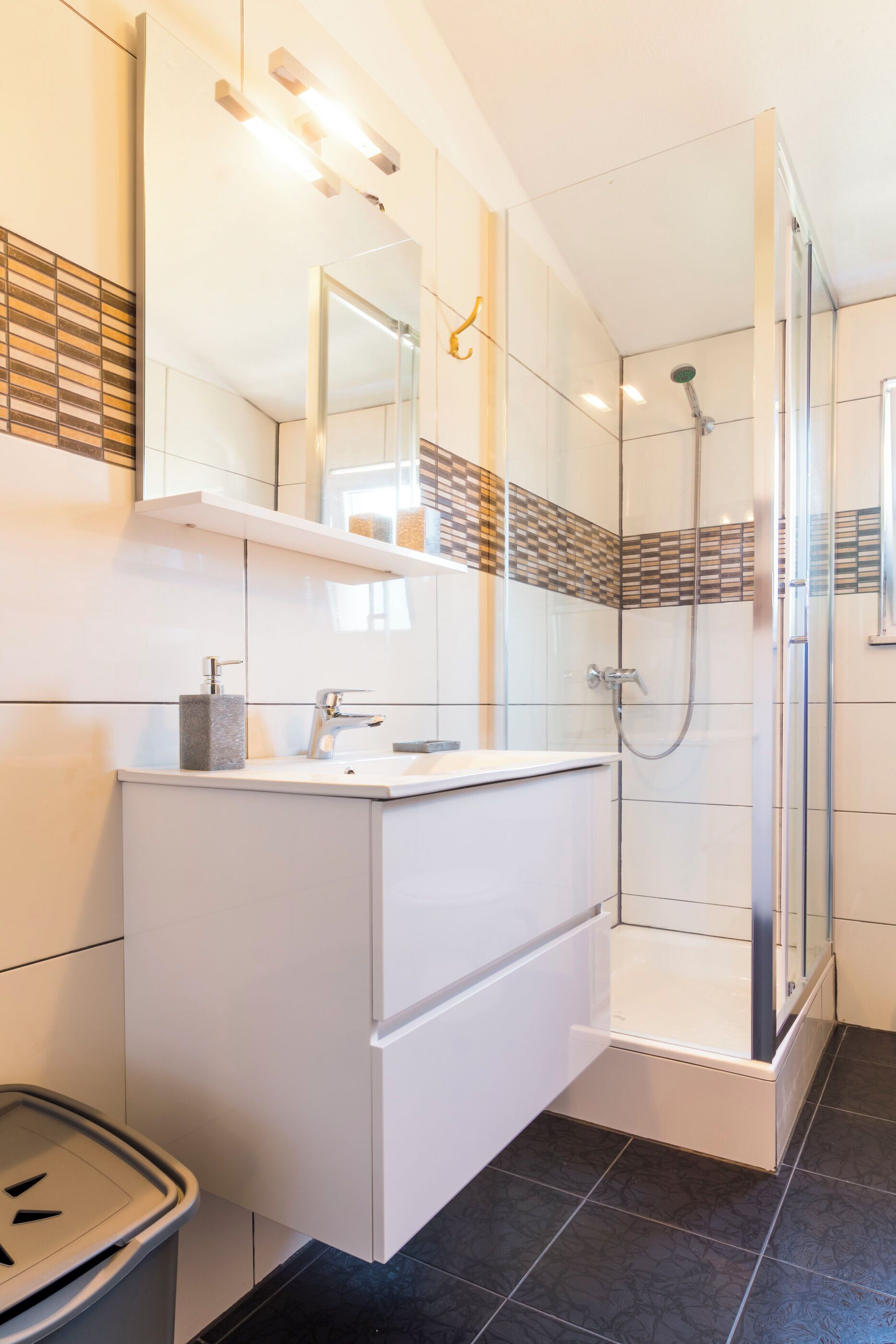 A modern bathroom with a glass-enclosed shower, white cabinetry, and a tiled floor.