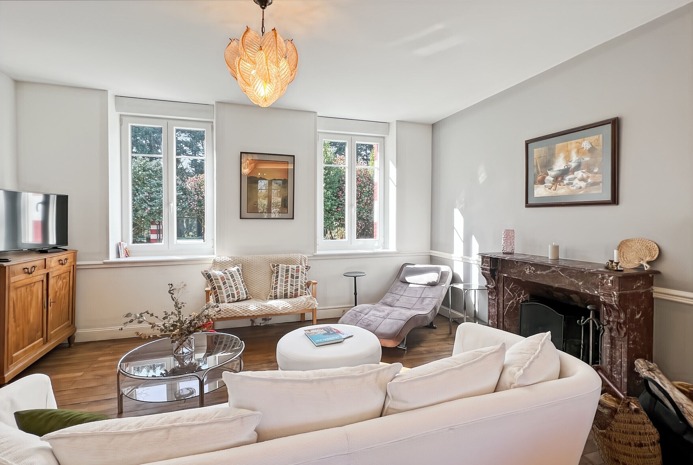 A living room with a sofa, armchair, and ottoman, a fireplace, and a television.