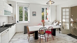 A modern kitchen with white cabinets, a black countertop, and a large window. - Renovated family home 14 sleeps 10 min from beaches, parking and wifi (Quéven)