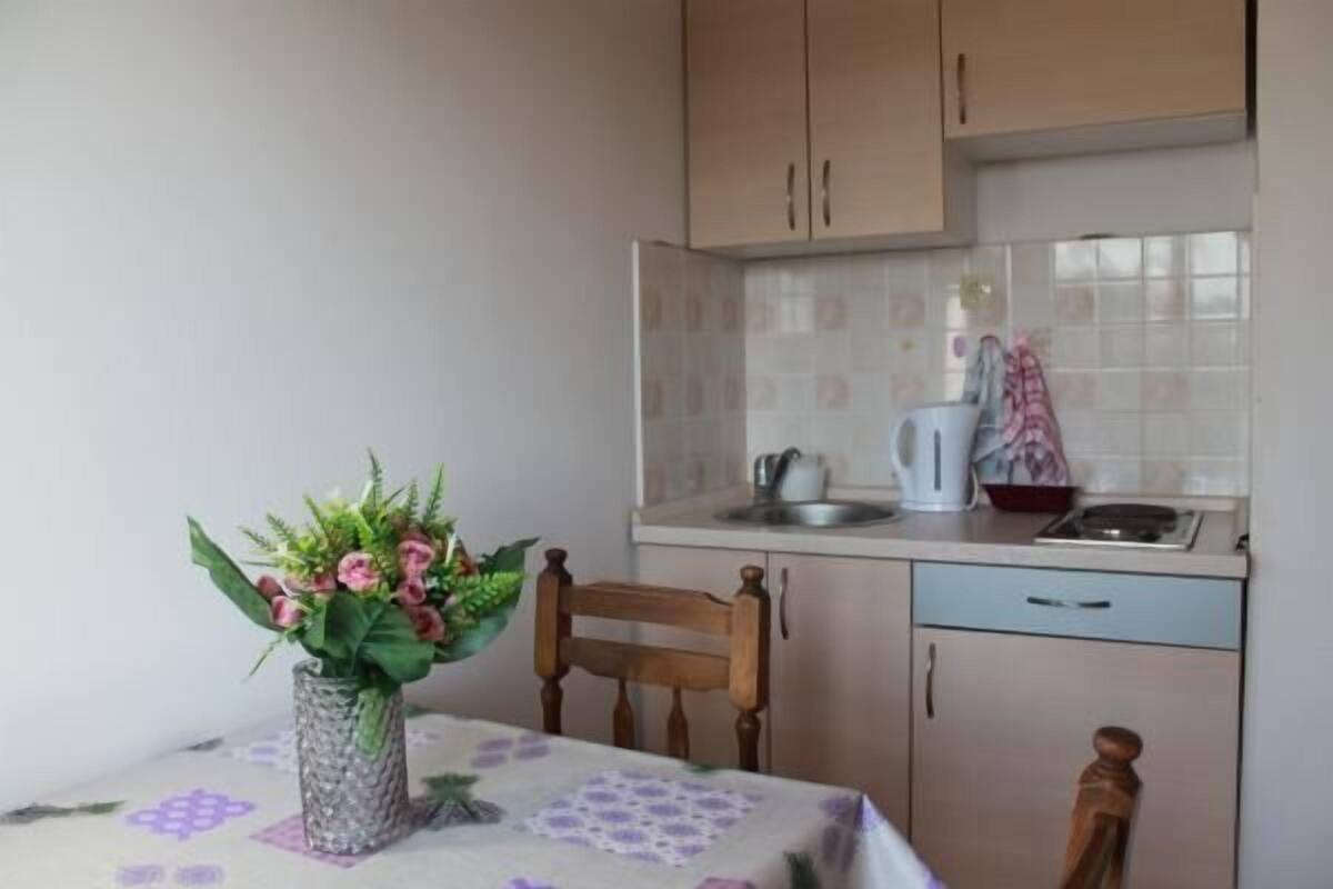 A kitchen with wooden cabinets, a tiled backsplash, and a dining table with a floral tablecloth.