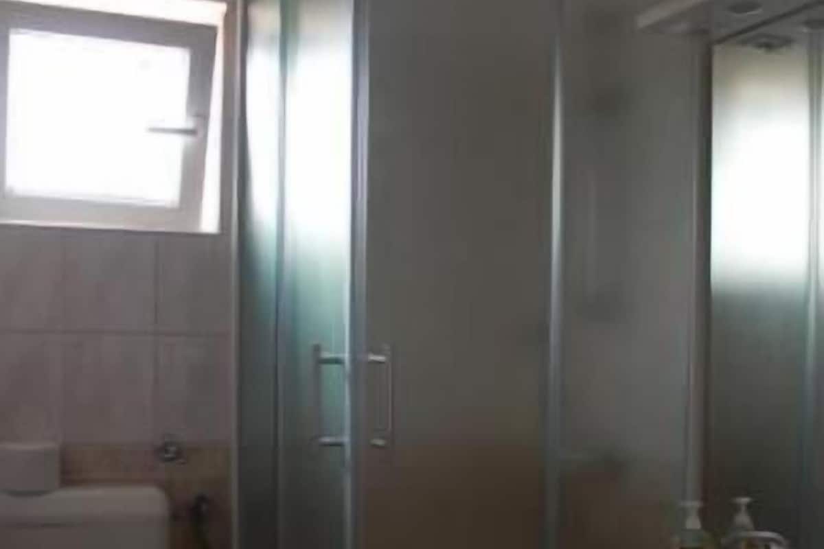 A bathroom with a glass-enclosed shower, a toilet, and a sink with a mirror.
