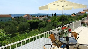 Ein Balkon mit Tisch, Stühlen und Sonnenschirm, mit Blick auf die umliegende Landschaft.