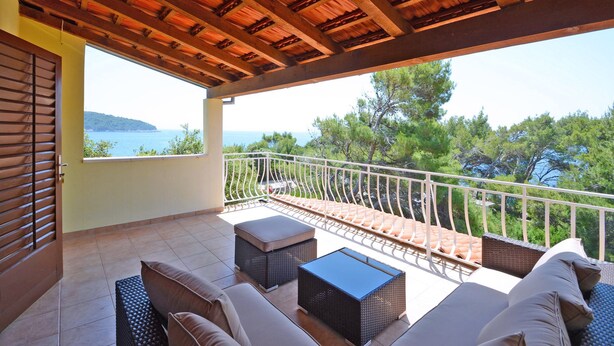 Un balcon doté d’un plafond en bois, de mobilier d’extérieur et offrant une vue sur la mer.