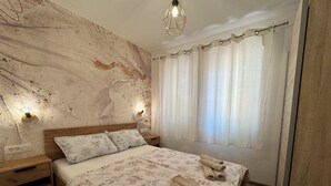 Ein Schlafzimmer mit einem hölzernen Kopfteil, floralem Bettbezug, einem Nachttisch und einem Beistelltisch.