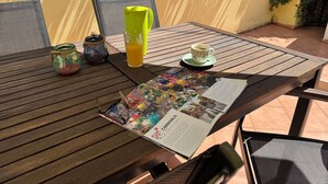Ein Holztisch mit einer Speisekarte, einem Orangensaftglas, einer Kaffeetasse und einem kleinen Einmachglas mit Henkel.