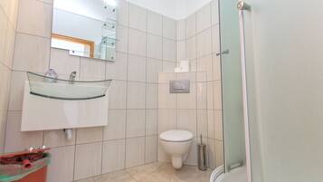 Une salle de bain avec un lavabo en verre, des toilettes et une douche.