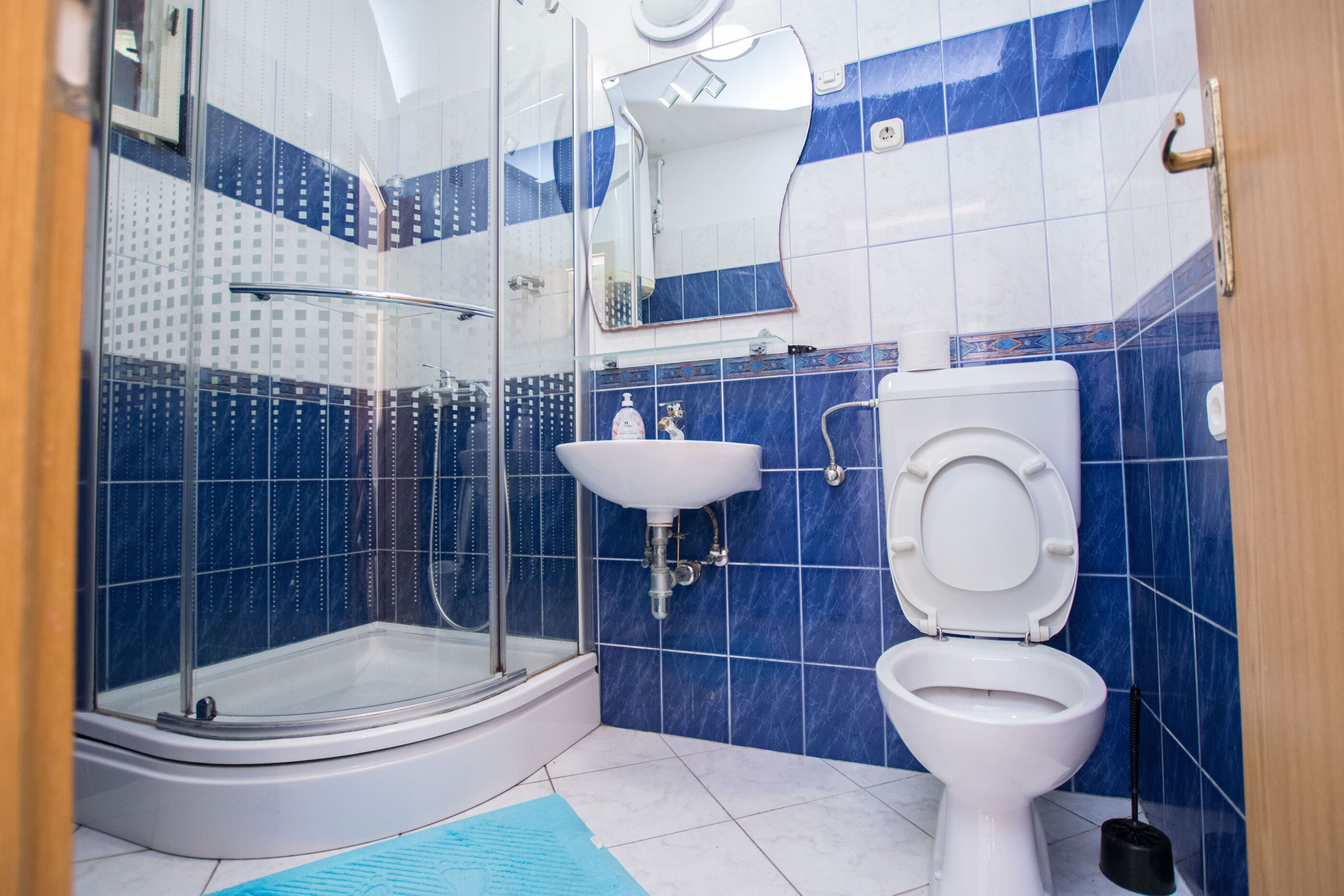 A bathroom with a glass-enclosed shower, a white sink, and a toilet.