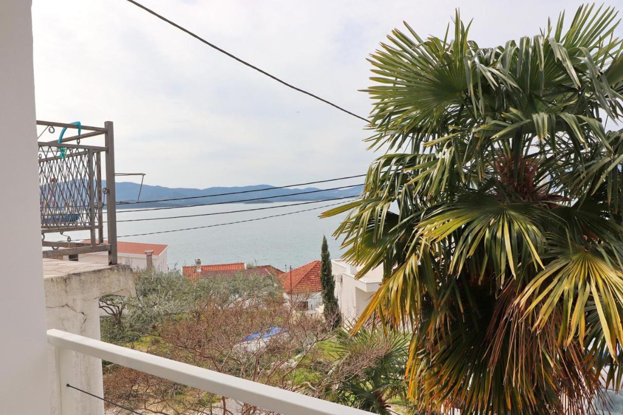 A balcony with a view of the sea and a bridge in the distance.