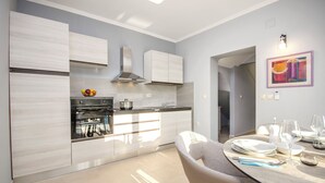 A modern kitchen with built-in appliances, a dining area with a table set for two, and a hallway leading to another room. - Apartments Maris (Tribunj)