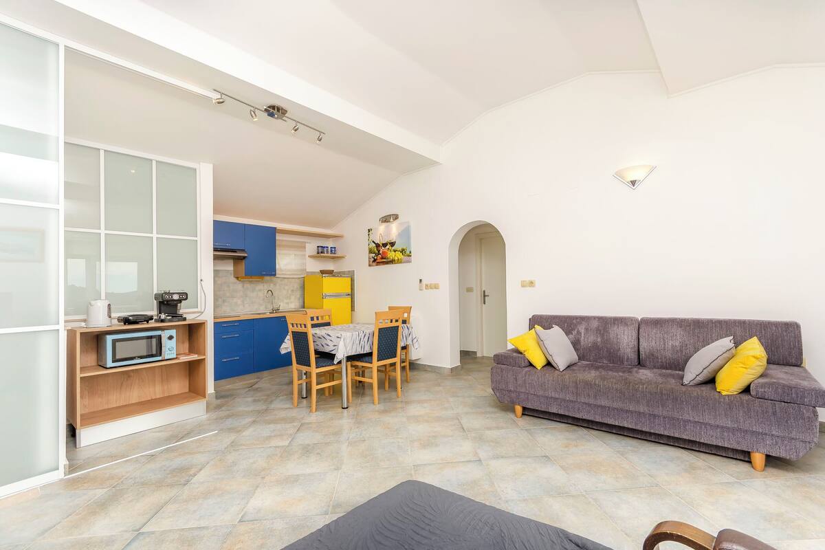 A compact living space with a kitchenette, dining area, and a sofa.