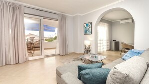 A modern living room with a sofa, a table, and a view of a balcony with outdoor furniture. - Apartments Maris (Tribunj)